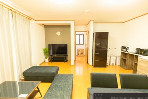 Cozy living space with a flat-screen TV, sofa, and kitchenette.