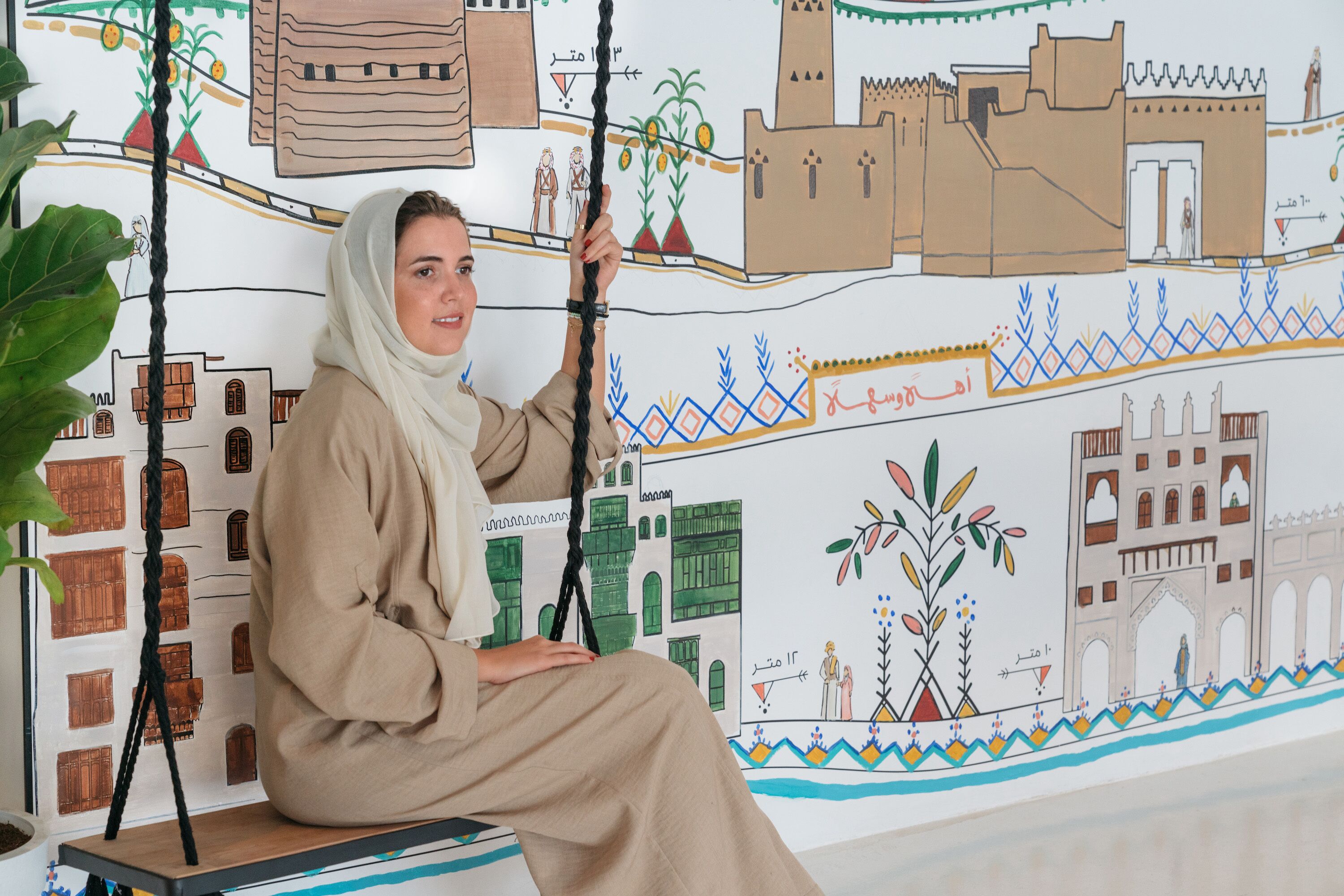 A person sitting on a swing with a wall mural in the background.