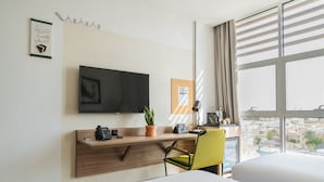 A hotel room with a bed, a desk with a phone, a plant, and a TV on the wall. - Shada Hotel Shatea (Jeddah)