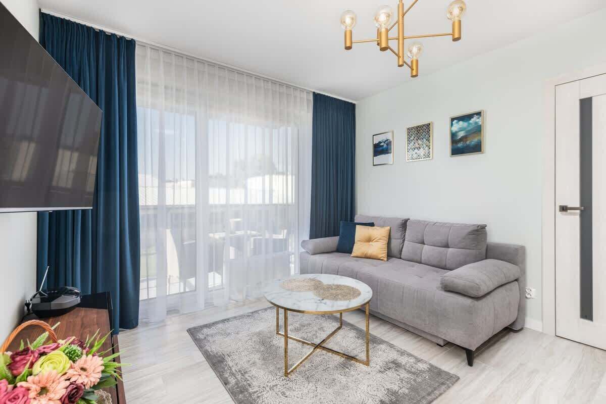 A modern living room with a grey sofa, a round coffee table, and a TV on the left.
