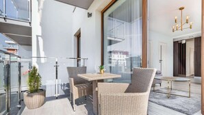 A modern balcony with wicker furniture, a small table, and a potted plant. - Comfortable Apartment | Balcony and Parking in Garage (Kolobrzeg)
