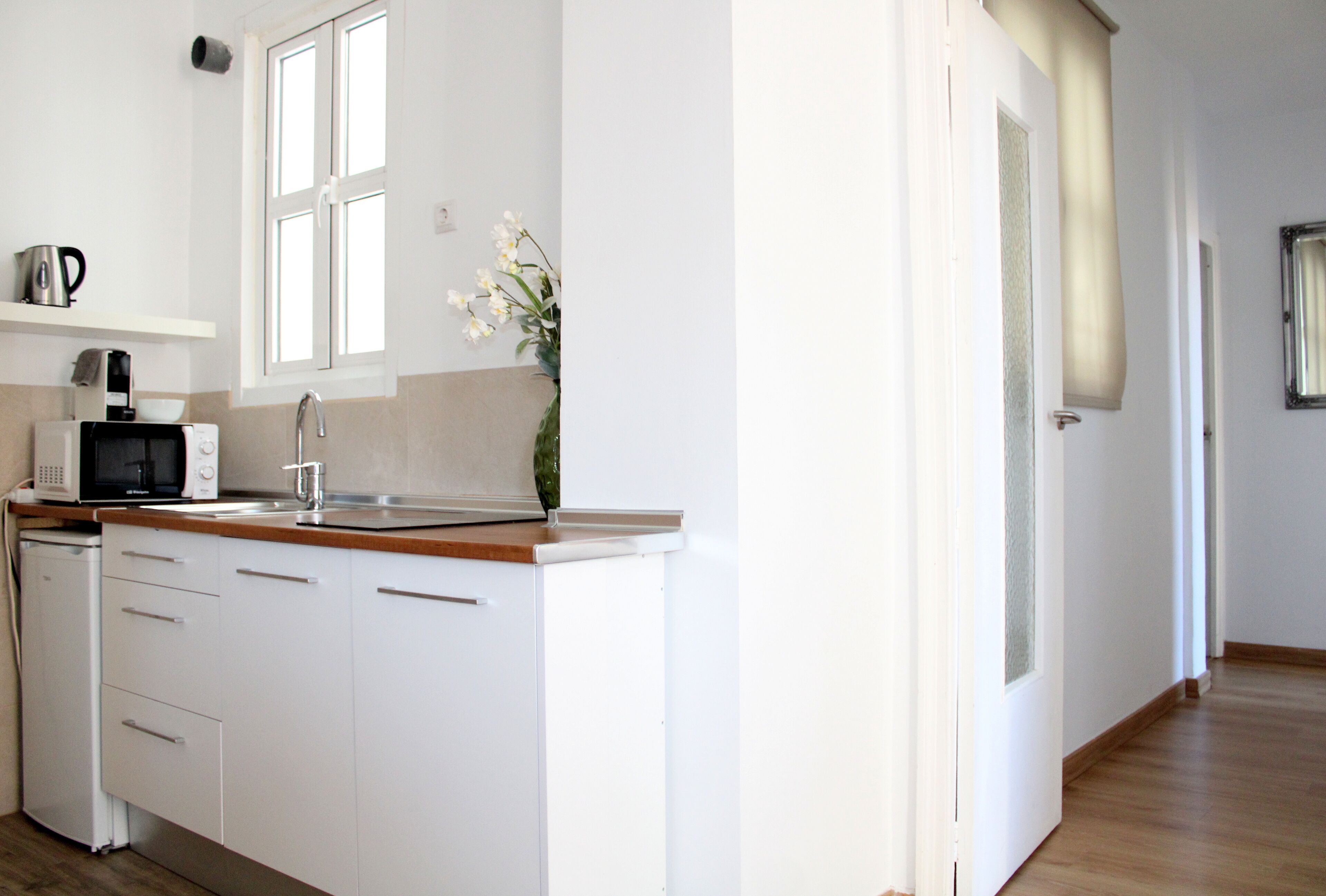 A kitchen with white cabinets, a microwave, a sink, and a window above the counter.