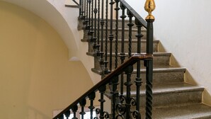 Una escalera con barandillas de metal negro ornamentado y un pasamanos de madera.