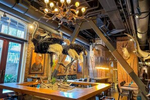 A restaurant interior with a large chandelier, wooden tables, and mounted animal heads on the walls.