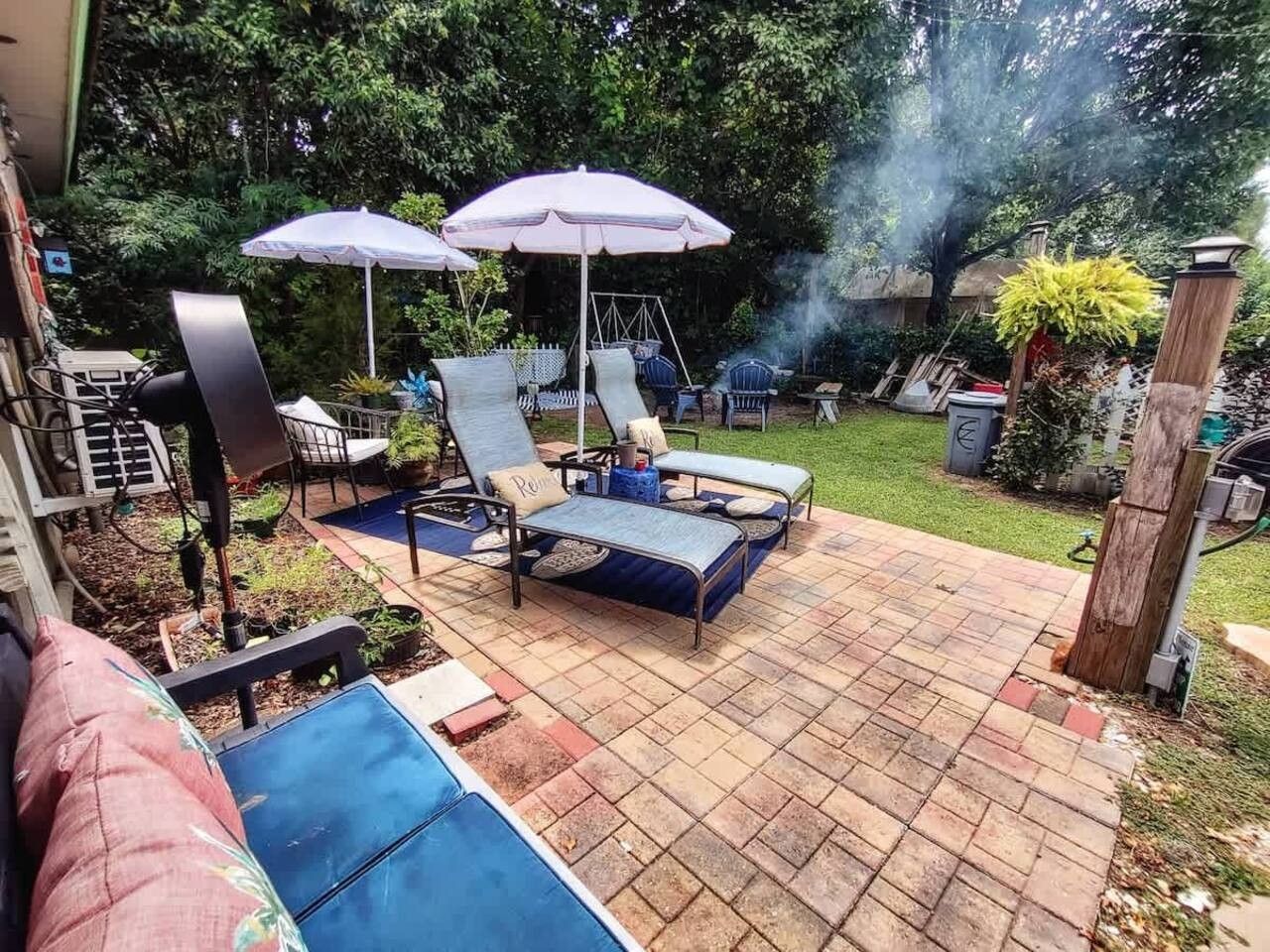 En udendørs patio med liggestole, et gyngestativ og en grill.