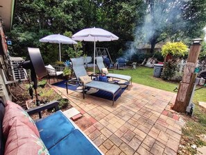 Eine Terrasse im Freien mit Lounge-Möbeln, einer Schaukel und einem Grill.