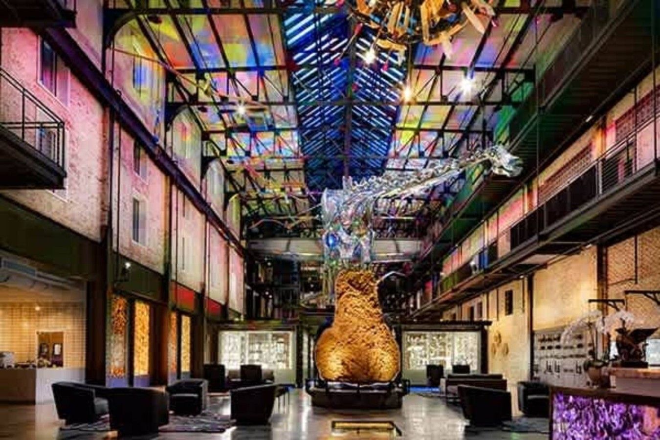 A spacious lobby with a central sculpture, high ceilings, and a modern industrial design.