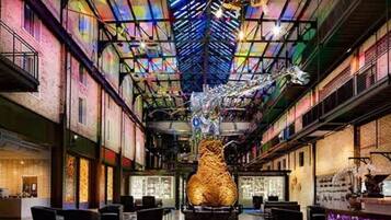 A spacious lobby with a central sculpture, high ceilings, and a modern industrial design.
