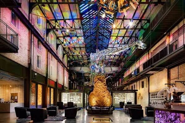 A spacious lobby with a central sculpture, high ceilings, and a modern industrial design.