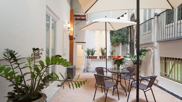 A patio with a table and chairs, surrounded by potted plants and a large umbrella. - Palazzo Marigliano - Don Aniello (Napoli)