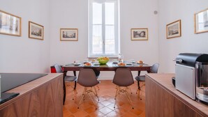 A dining area with a large table, chairs, a grill, and framed pictures on the walls. - Don Francesco: an apartment with spectacular views in Palazzo Marigliano (Napoli)