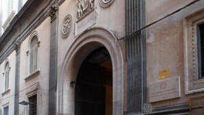 A historic building facade with classical architectural elements, including an arched doorway and decorative reliefs. - Don Francesco: an apartment with spectacular views in Palazzo Marigliano (Napoli)
