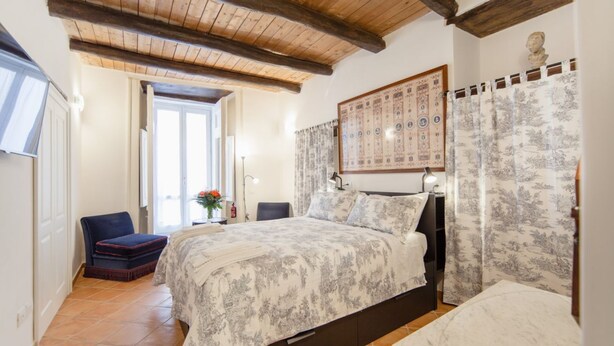 Een slaapkamer met een bed, een stoel, een bureau en een raam.