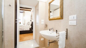 Een moderne badkamer met een witte wastafel, een spiegel met gouden lijst en een douchehoek.