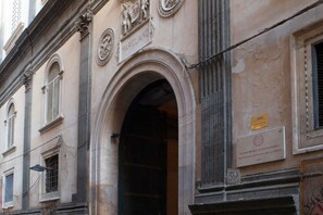 A historic building facade with classical architectural elements, including an arched doorway and decorative reliefs.