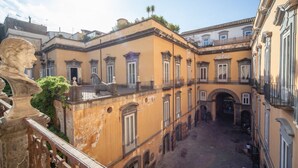 A courtyard with a central archway, surrounded by buildings with balconies and windows.