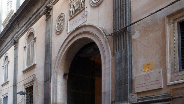 A historic building facade with classical architectural elements, including an arched doorway and decorative reliefs.