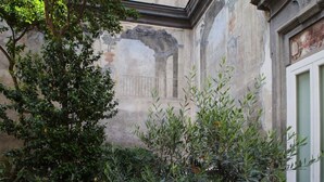A courtyard with a bench, potted plants, and a mural on the wall.