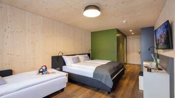 Ein modernes Schlafzimmer mit einem großen Bett, einem kleineren Bett und einem Schreibtisch mit Fernseher.
