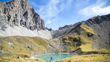 A mountainous landscape with a clear lake and a person running.