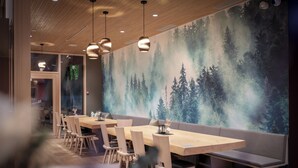 A restaurant with wooden tables and benches, pendant lighting, and a forest mural on the wall. - AVES Hotel Savognin (Surses)