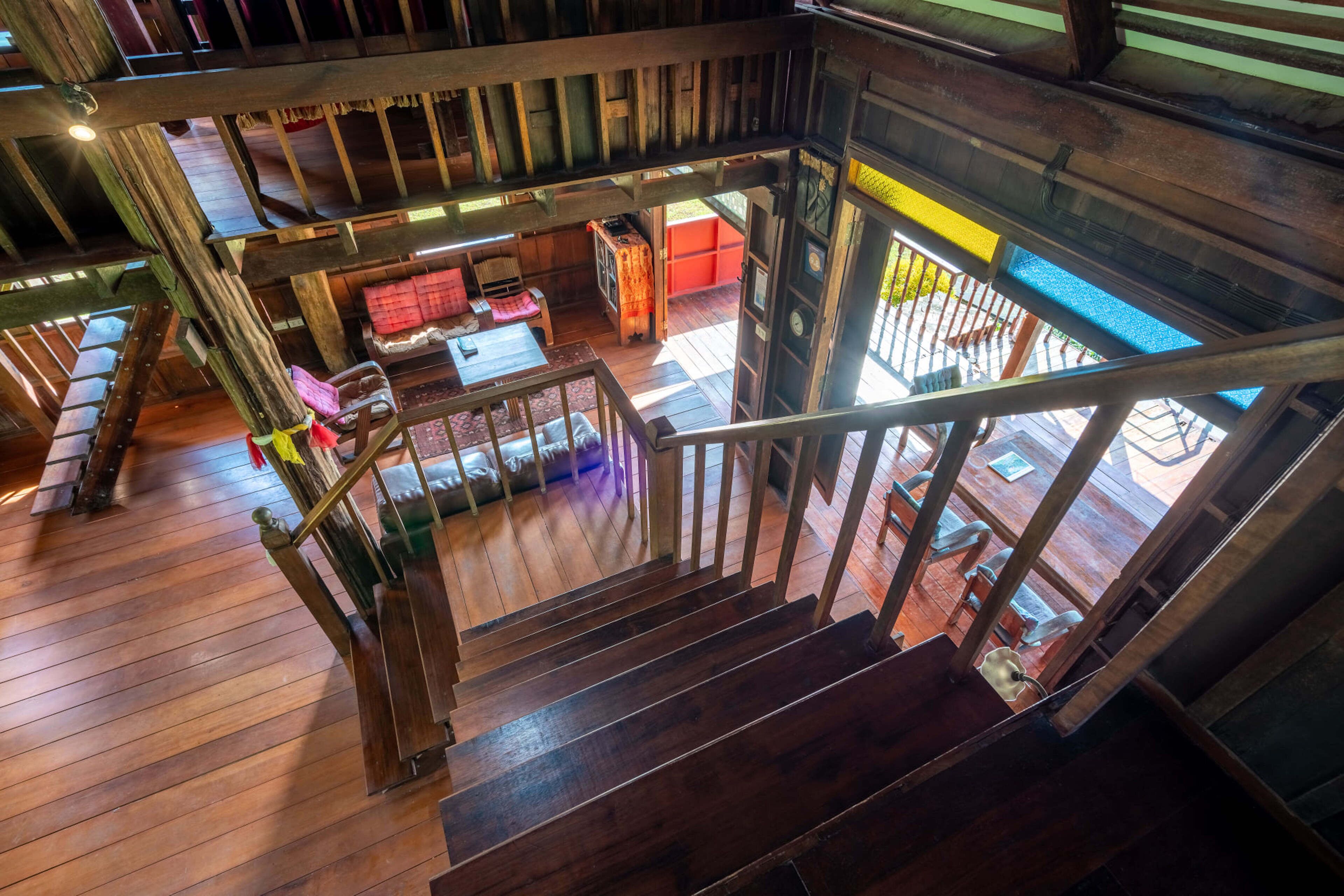 Una escalera de madera conduce a un nivel inferior, con vista a una sala de estar acogedora que incluye un sofá y una mesa.