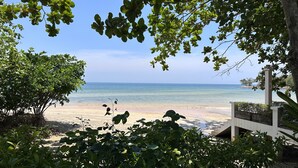 Vista sulla spiaggia, cielo sereno, spiaggia sabbiosa e vegetazione rigogliosa.