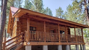 A wooden cabin with a balcony, concrete foundation, and a number '7' sign. - Circle Pine Ranch-"The Real Log Cabin Experience" (Alpine)