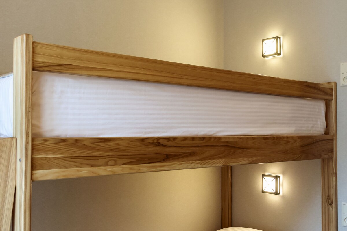 Un lit superposé à deux niveaux, chaque niveau étant équipé d’un oreiller et d’une lampe au-dessus.