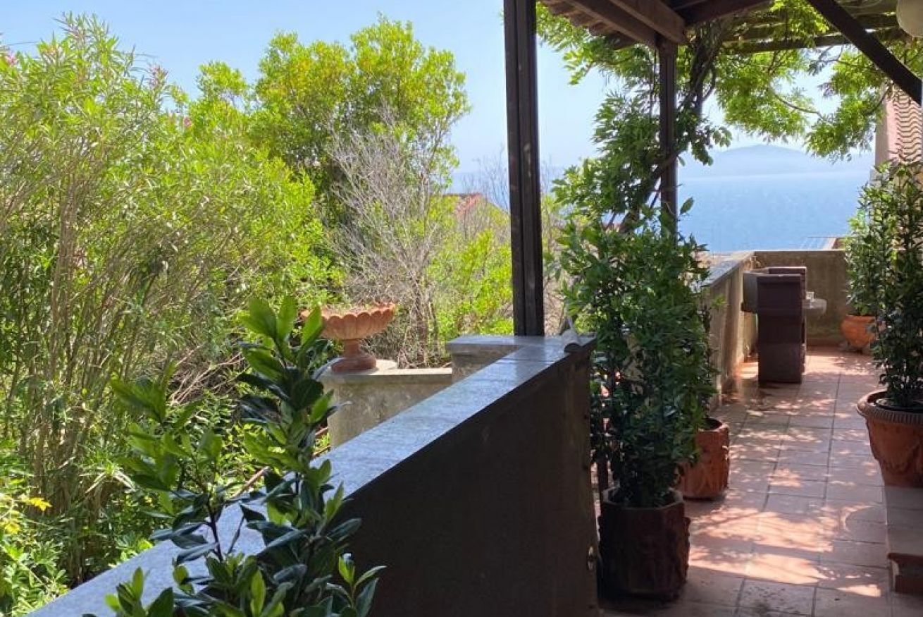 Un balcone con piante in vaso, una mensola in pietra e vista sul mare.