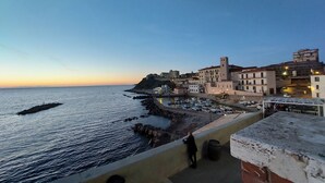 A coastal town with buildings along the waterfront, a rocky shoreline, and a clear sky. - Elegant apartment with view of the sea (Piombino)