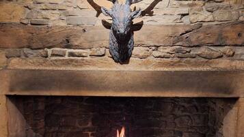 Una chimenea de piedra con un venado montado en la pared y fuego encendido.