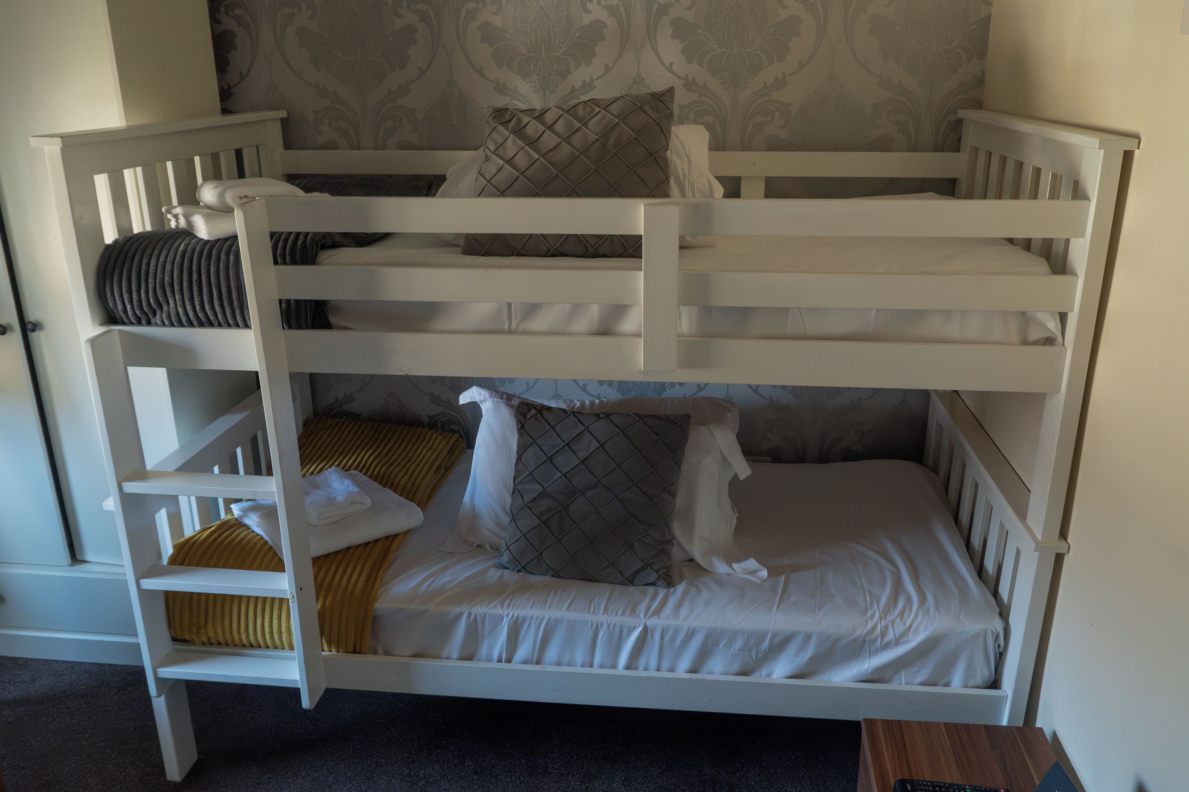 Una cama litera con cabecera, almohadas y una manta.
