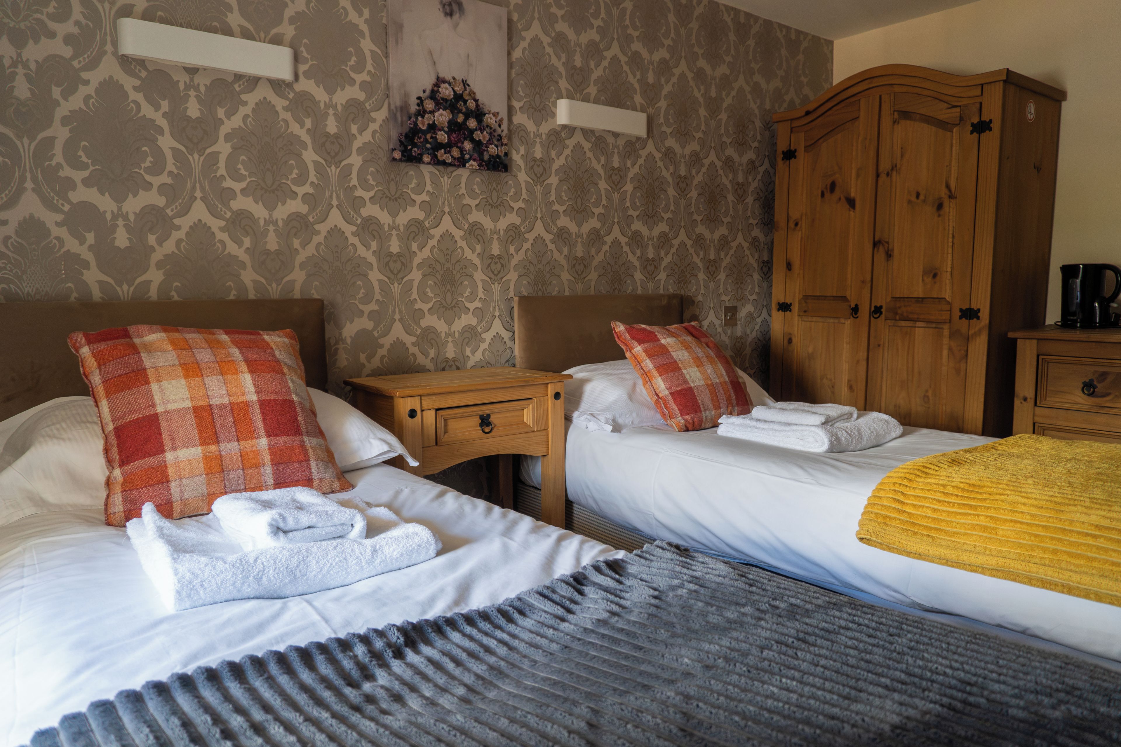 Une chambre d’hôtel avec deux lits, une armoire en bois, une table de chevet et une œuvre d’art accrochée au mur.