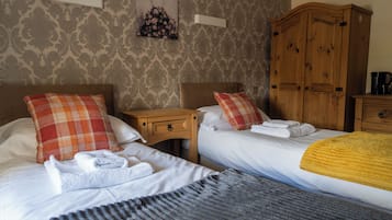 Habitación de hotel con dos camas, un armario de madera, una mesita de noche y una obra de arte colgada en la pared.