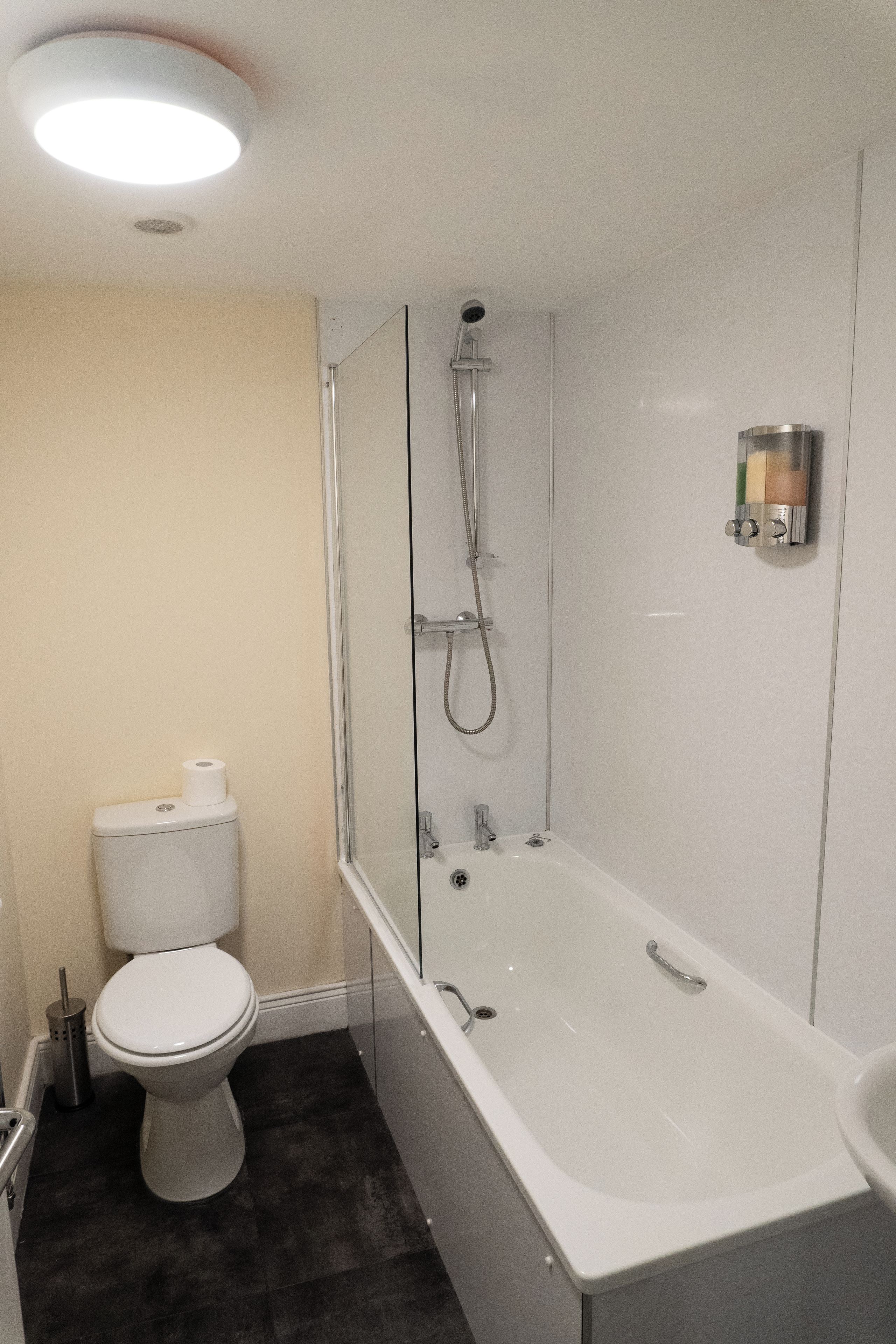 A modern bathroom with a white toilet, a glass-enclosed shower, and a white bathtub.