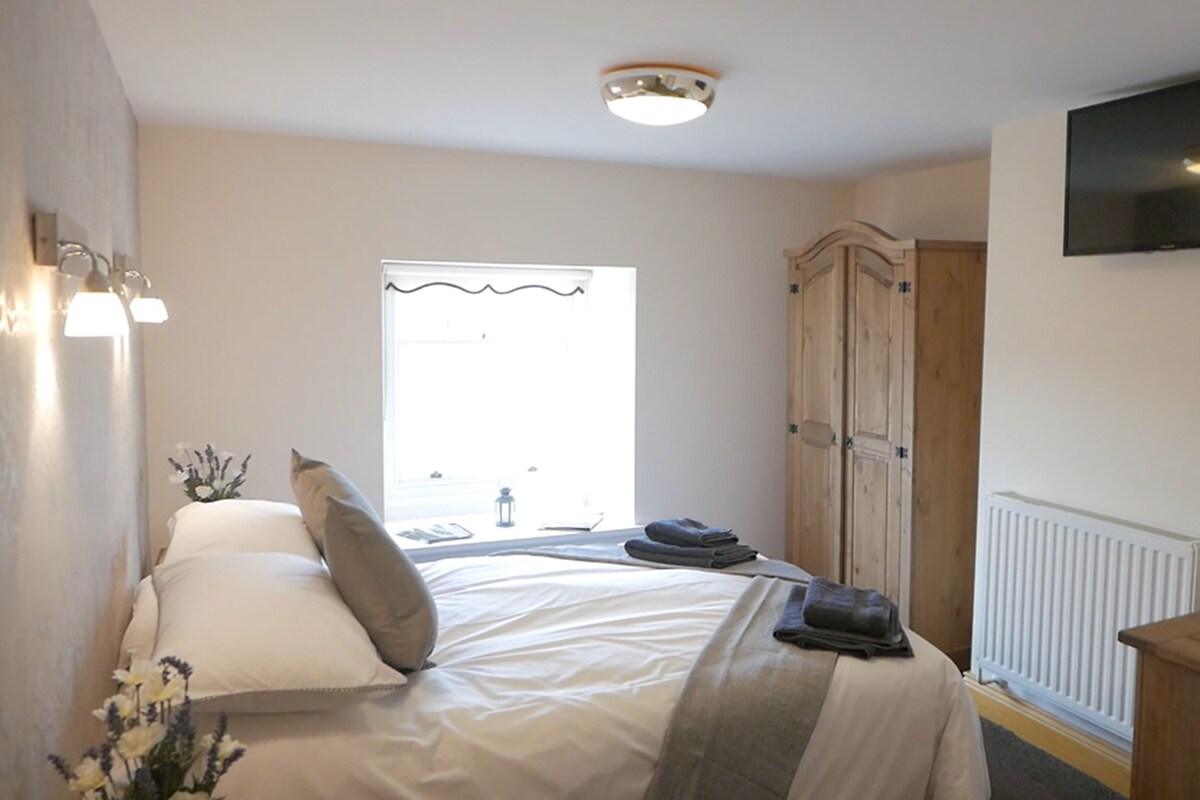 A bedroom with a bed, a wardrobe, a radiator, and a TV mounted on the wall.