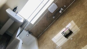 A bathroom with a bathtub, a sink, and a shower unit. - Manor House Inn (Haltwhistle)