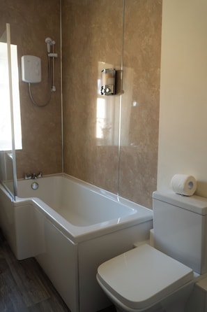 A bathroom with a bathtub, toilet, and a shower. - Manor House Inn (Haltwhistle)