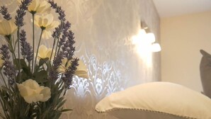 A room with a white pillow, a vase with flowers, and a wall with a light fixture. - Manor House Inn (Haltwhistle)