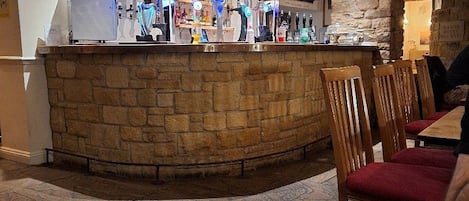 A bar area with a stone counter, wooden chairs, and a sign indicating a service area.