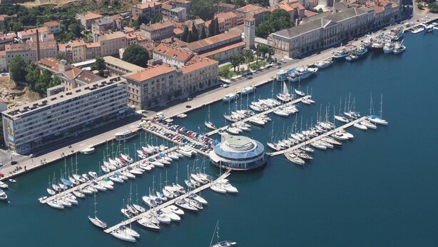 An aerial view of a marina with numerous boats docked, surrounded by a cityscape with historic buildings and a large hotel structure. - Apartment for two person near the sea and city center,WIFI,airconditioning,BBQ,parking (Pula)