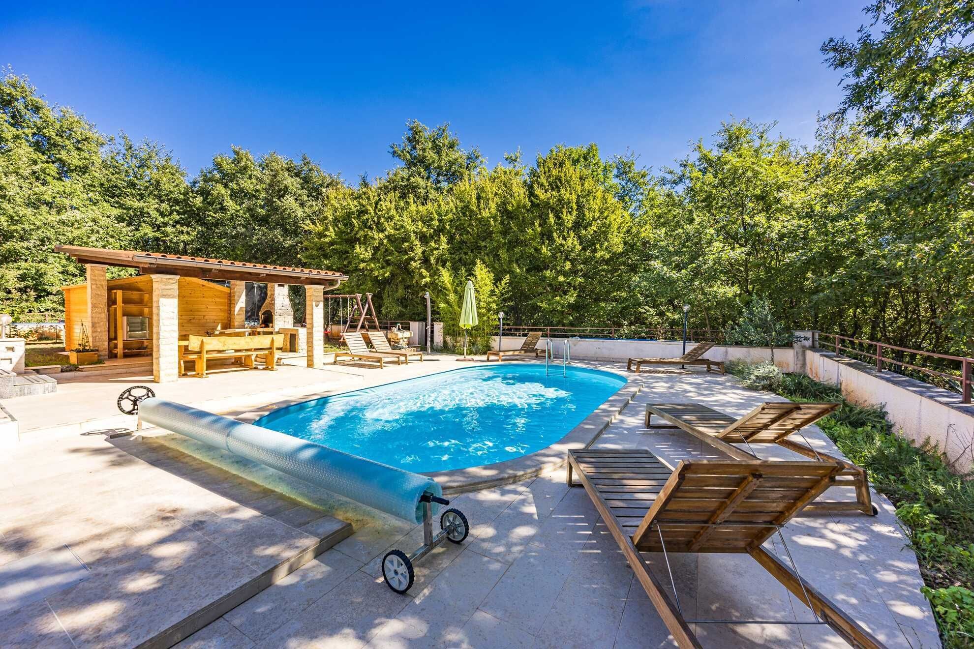 Une piscine avec une terrasse en bois, des chaises longues et une petite construction en bois dotée d’une cheminée.
