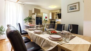 Un coin repas avec une table dressée pour quatre personnes, une plante en pot et un vase de roses.