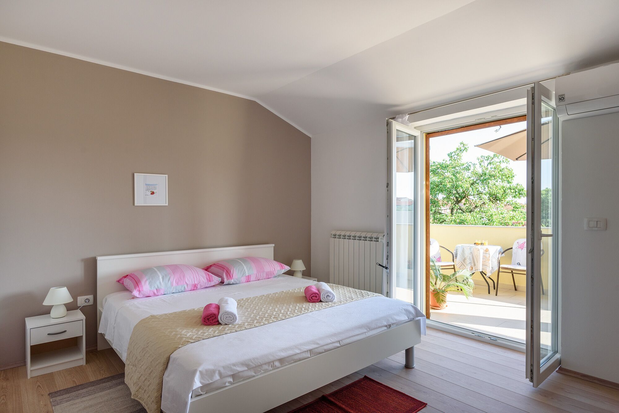 A bedroom with a bed, bedside table, and a view of an outdoor patio.
