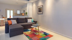 Een moderne woonkamer met een grijze modulaire bank, een klein rond tafeltje en een kleurrijk vloerkleed.