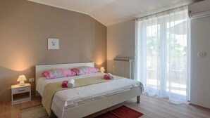 Een slaapkamer met een bed, nachtkastjes, een radiator en een raam met gordijnen.