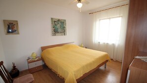 A bedroom with a wooden bed, a chair, a nightstand, and a ceiling fan.