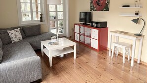 A living room with a grey sofa, white coffee table, and a red cabinet with a television on top.