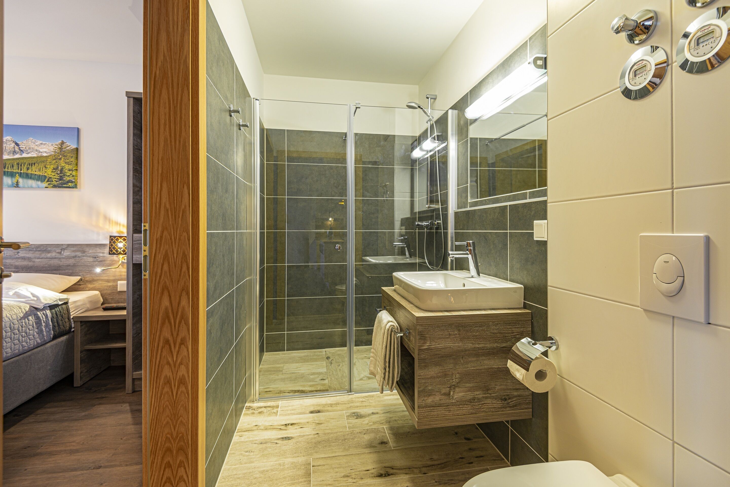 Une salle de bain moderne avec une douche à parois de verre, un meuble-lavabo en bois et un grand miroir.